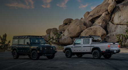 A white 2026 Quartermaster and black 2026 Station Wagon facing each other in the mountain area.