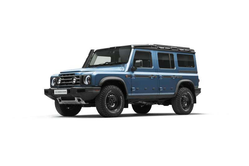 A light blue, Ineos Grenadier Station Wagon with a double cab and four doors is set against a black background. The front features bold round headlights.