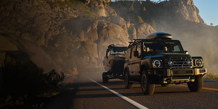 A black 2026 Station Wagon towing a boat on a trailer in the mountain area.