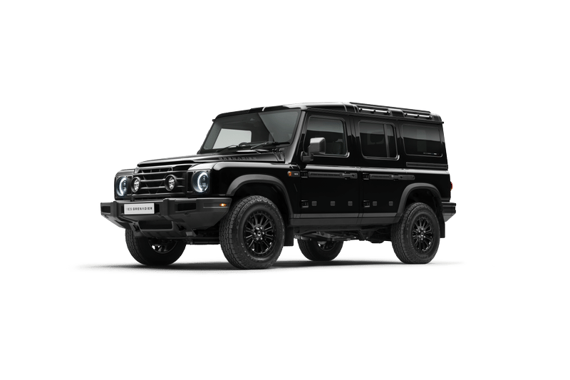 A black, Ineos Grenadier Station Wagon with off-road tires and sleek design is showcased on a dark background, conveying toughness and sophistication.