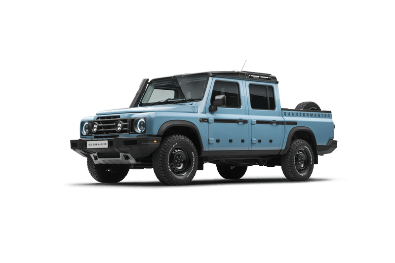 A light blue, Ineos Grenadier Quartermaster with a double cab and four doors is set against a black background. The front features bold round headlights.