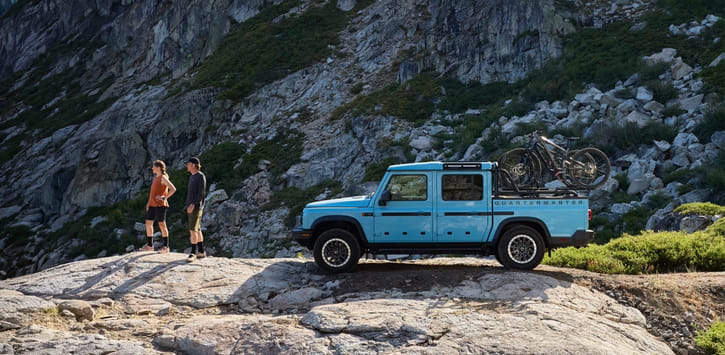 A blue 2026 Quartermaster parked on a mountain with bikes on a bike rack.