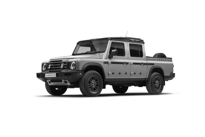 Silver Ineos Grenadier Quartermaster. Features include a four-door cab, off-road tires, and a visible spare tire.