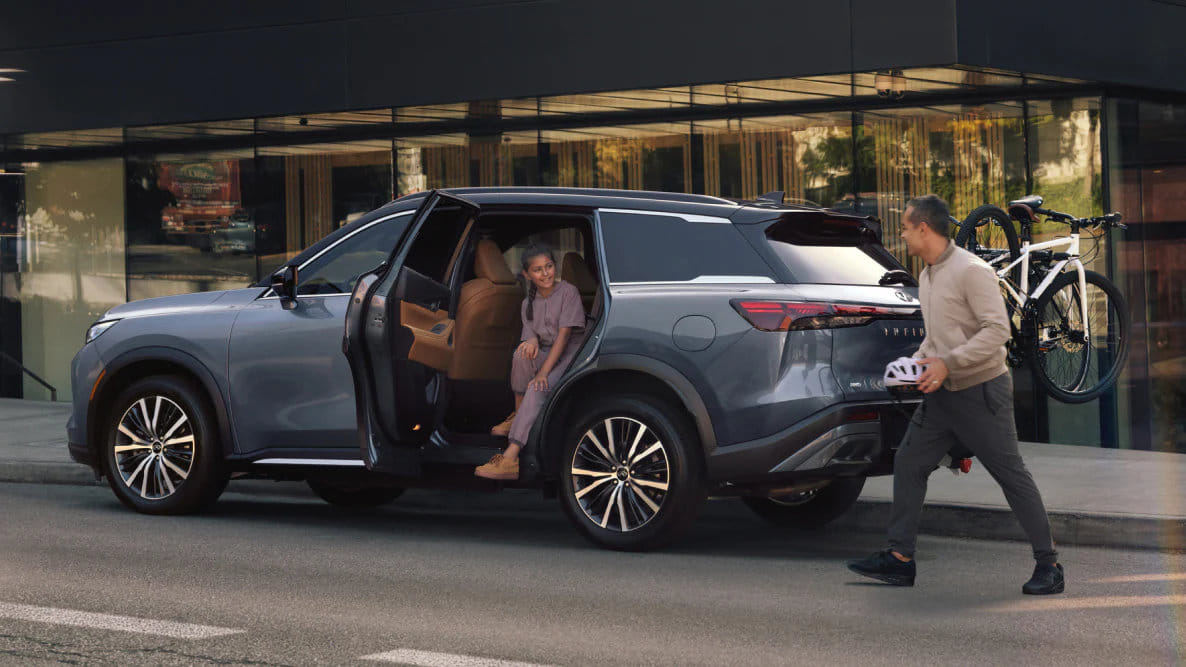 Woman on phone calling Nissan roadside assistance with her bag placed on the hood of her vehicle