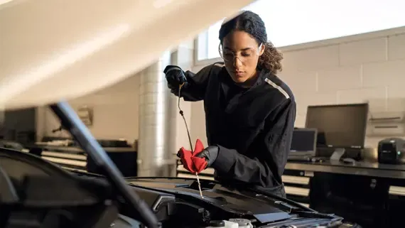 INFINITI technician conducts engine bay inspection during routine dealership service.