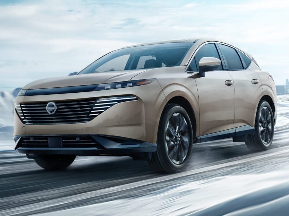A sleek beige 2026 Nissan Murano drives on a snowy road, showcasing its modern design and advanced features in a winter setting.