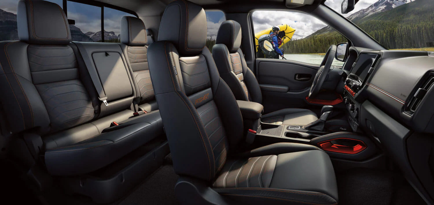 The comfortable interior of the 2026 Frontier Crew Cab, with the rear under-seat storage compartment open to show its versatility.