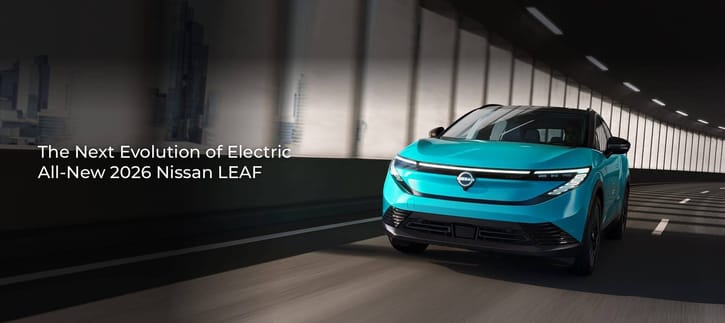 A turquoise 2026 Nissan Leaf EV drives through a modern, well-lit tunnel, highlighting its futuristic design and sleek LED headlights.