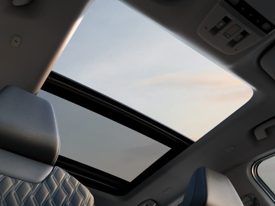 View from inside a 2026 Nissan Murano showing a panoramic sunroof and a glimpse of the sky at sunset, with plush seat upholstery visible.