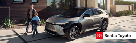 toyota mirai standing in front of a house, a smiling man with a child walks past it
