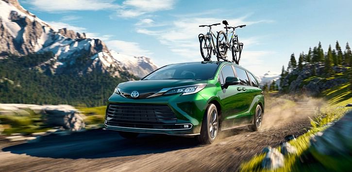 A green Sienna driving on the mountain road.