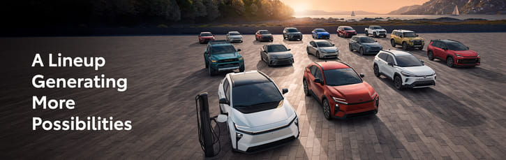 A group of diverse cars arranged on a vast paved area at sunset, with "A Lineup Generating More Possibilities" text. The scene conveys innovation and variety.