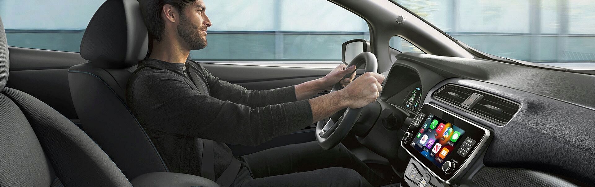 Cockpit view with a man driving a Nissan Leaf EV.