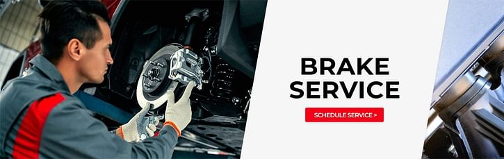 A mechanic looks at the brakes rotor while a car is on a lift