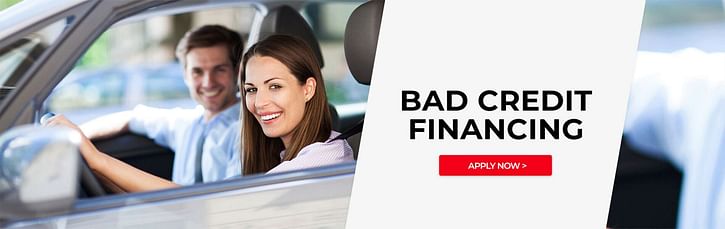 A couple smiling in a car during the day - Bad Credit Financing