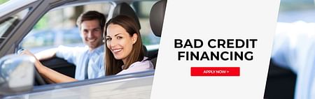 A couple smiling in a car during the day - Bad Credit Financing