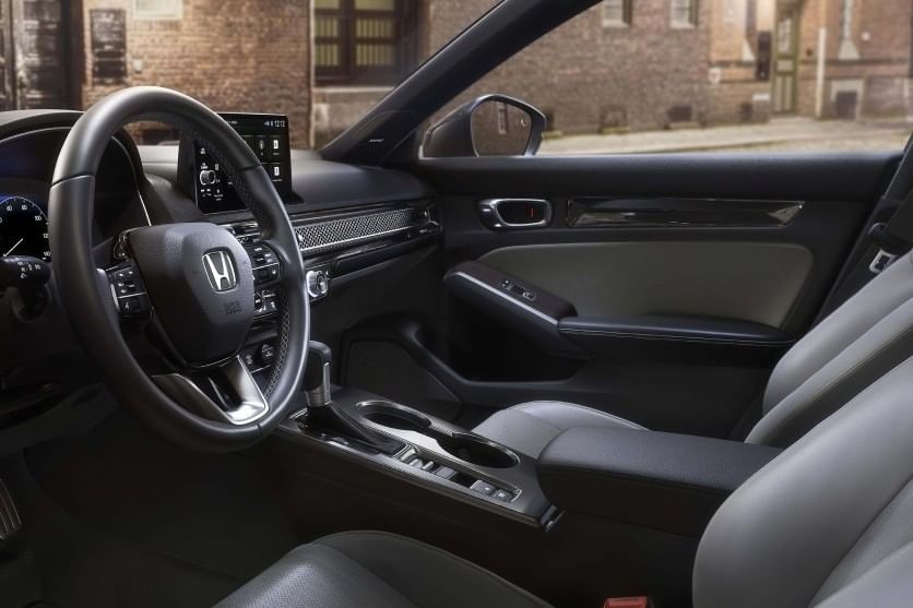 Interior of a 2025 Honda Civic Hatchback featuring a sleek dashboard, a modern infotainment display, leather seats, and an elegant design.