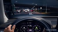 The view from the perspective of a driver driving on the highway at night with the Digital Instrument Cluster and Head-Up Display turned on