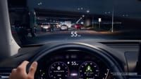 The view from the perspective of a driver driving on the highway at night with the Digital Instrument Cluster and Head-Up Display turned on