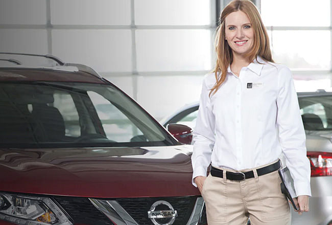 Woman in white shirt stands in front of red vehicle