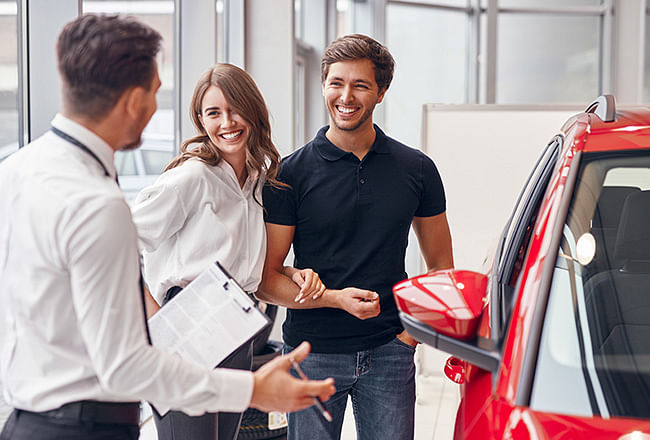 A salesman presenting a car to a smiling couple