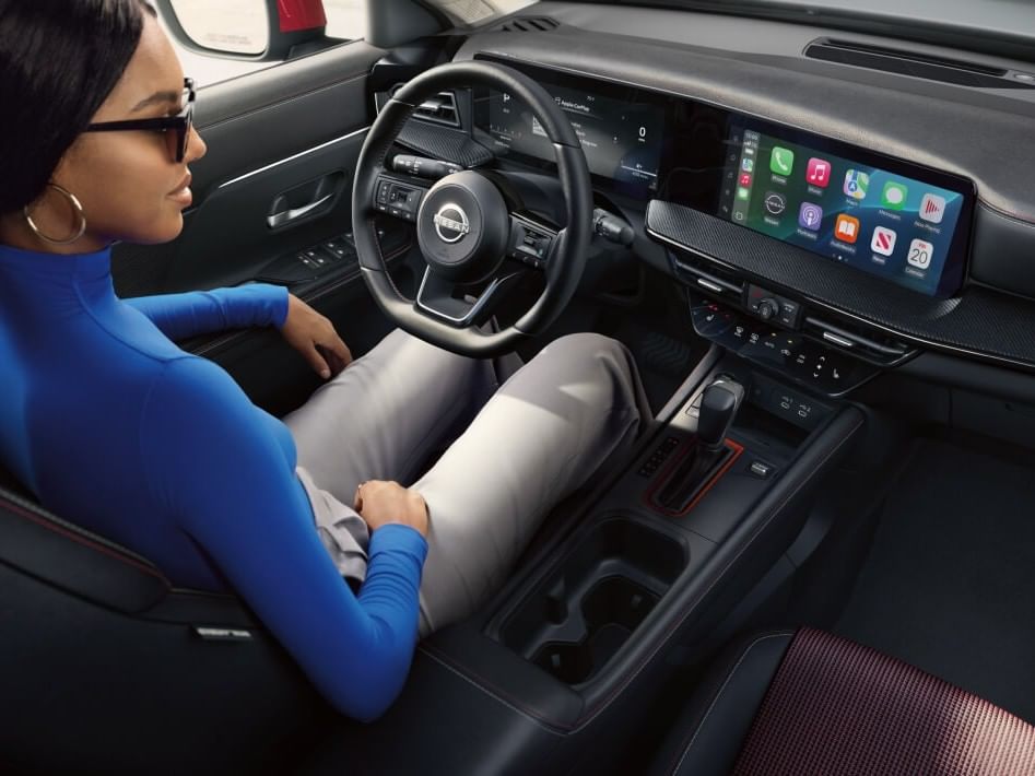 Inside of a 2026 Nissan Kicks, featuring a sleek dashboard with dual screens displaying smartphone apps and vehicle controls, enhancing driver experience.