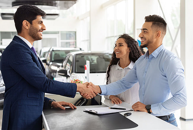 A smiling man shakes hands with salesman