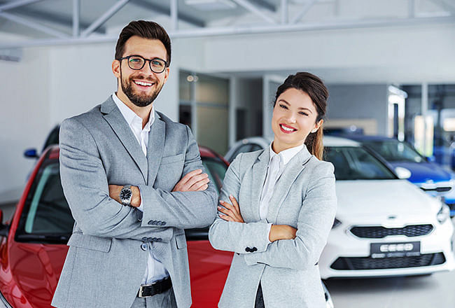 A Smiling vendor couple, cars in the background