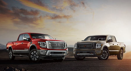 Two Nissan Titans parked in the mountain area overlooking the sunset.