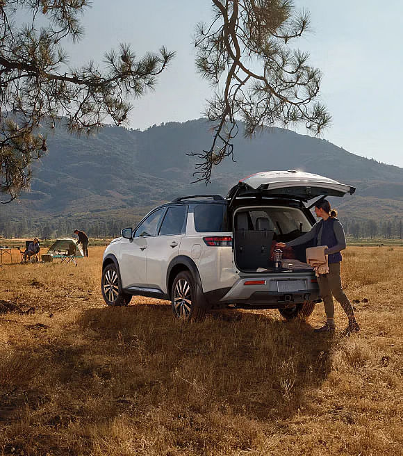 A woman loading a white Nissan Pathfinder in the outdoors