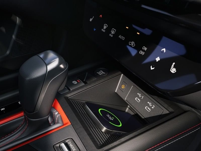 Close-up of a 2026 Nissan Kicks' center console featuring a gear shift, wireless charging pad, and control buttons for climate and features.