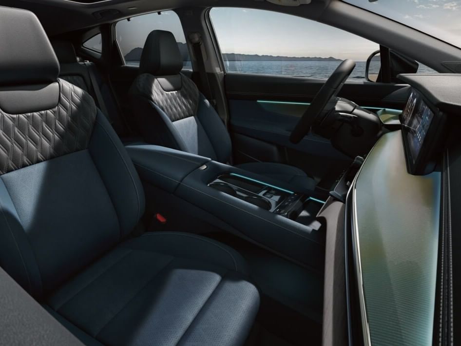Interior of a 2026 Nissan Murano featuring sleek blue and black seating, an illuminated dashboard, and a panoramic window view.