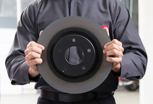 A service technician holding a new brake disc