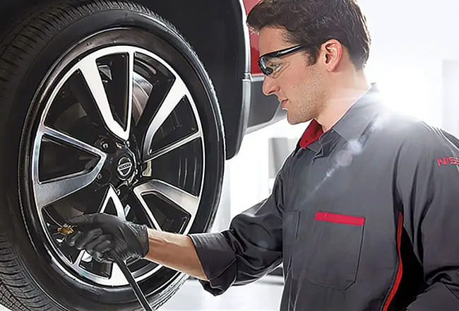 A car mechanic inflates a vehicle's wheel