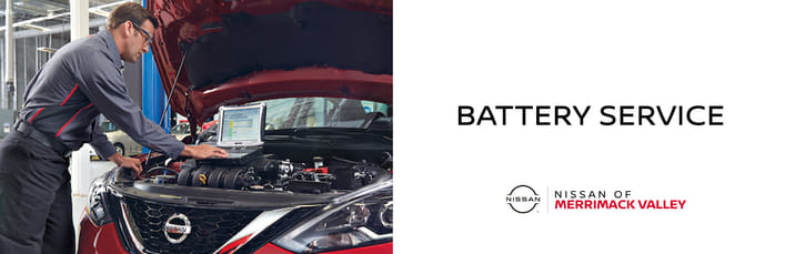 A banner for Battery Service at Nissan of Merrimack Valley showing a mechanic running diagnostics on an engine with a laptop.