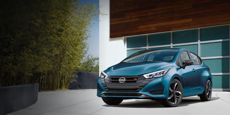 2025 Nissan Versa parked in a driveway in front of a modern garage.