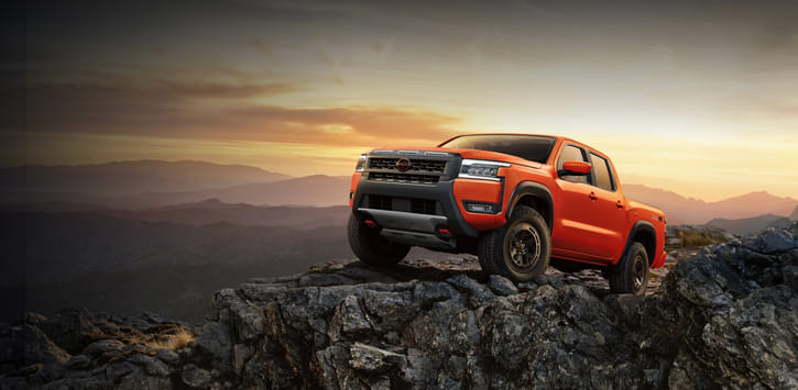 2025 Nissan Frontier PRO-4X on a rocky outcrop in the mountains with the sunset behind.