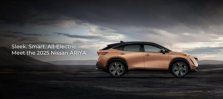 A side profile of a copper and black 2025 Nissan ARIYA electric crossover parked in a dramatic, rugged landscape under a cloudy sky.
