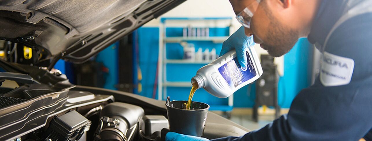 A mechanic pouring oil into the engine