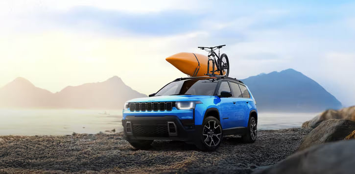 2026 Jeep Cherokee parked on a rocky beach with a kayak and part of a bike strapped to its roof rack