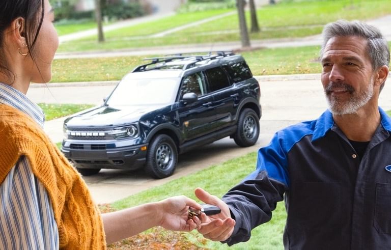 Un técnico de servicio de Ford recibiendo las llaves del auto de una mujer
