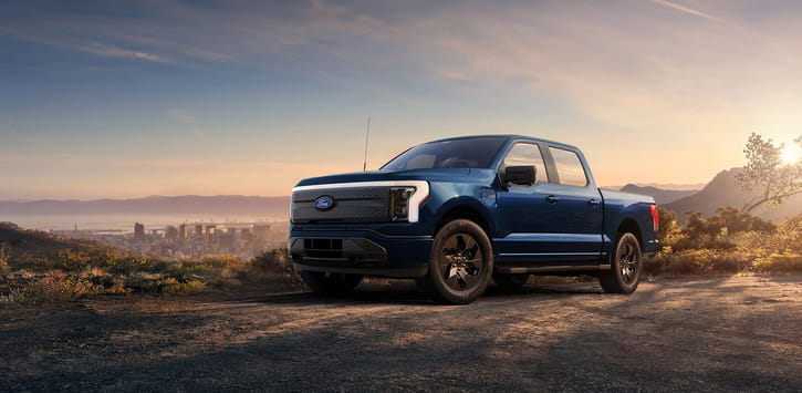 2025 Ford F-150 Lightning parked on a hilltop overlooking the city skyline.