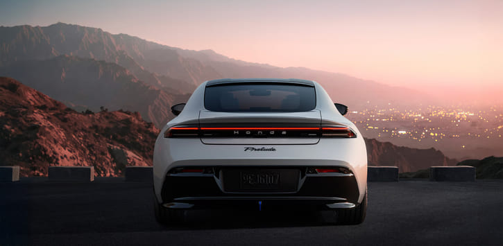 Rear view of a white 2026 Prelude parked on a hill overlooking the city skyline at sunset.