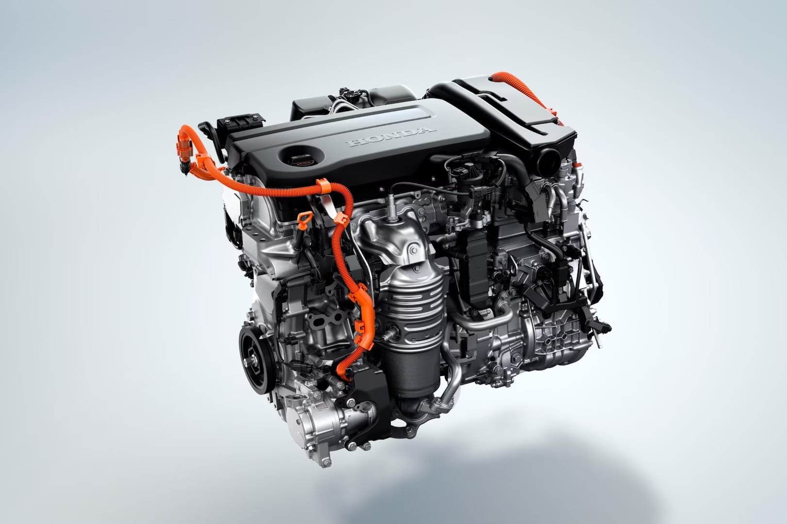 Close-up of a modern car engine with visible metallic components and bright orange cables, labeled with the brand name, on a light background.