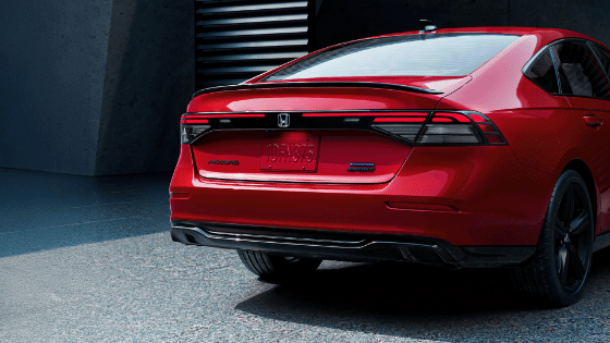Rear Passenger 7/8 of 2026 Honda Accord in Radiant Red Metallic in minimalistic urban courtyard environment, showing LED taillights.
