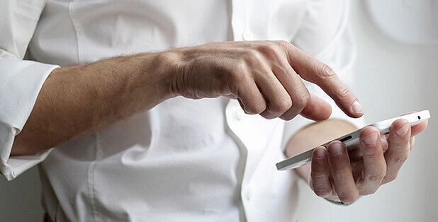 A man in white shirt using a bright smartphone