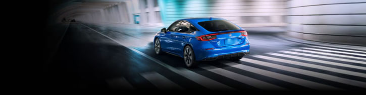 The 2025 Honda Civic Hatchback Sport Touring Hybrid in Boost Blue Pearl driving through underground tunnel