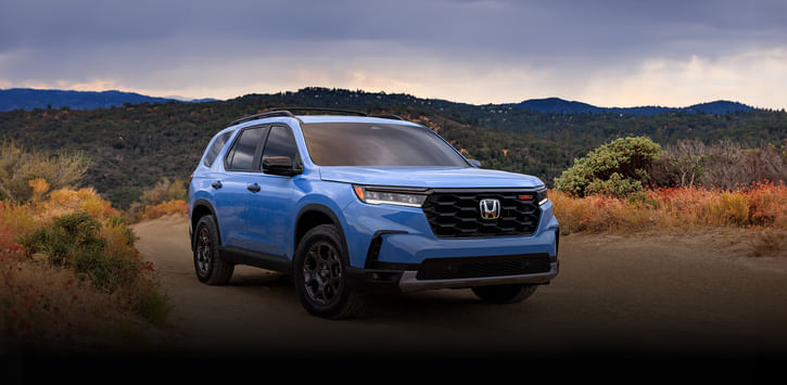 2025 light blue Pilot parked in middle of the desert amid desert plants.
