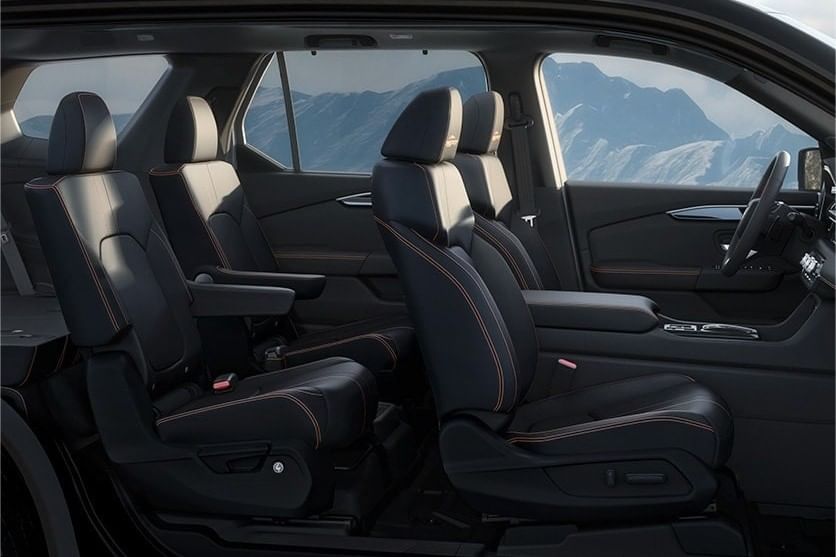 Interior view of a 2025 Honda Pilot showcasing black leather seats with orange stitching, designed for comfort and style, against a mountainous backdrop.