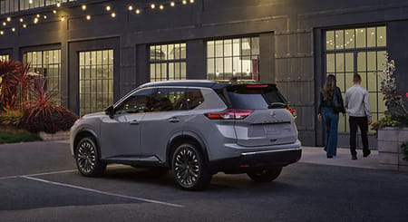 2026 Rogue parked in front of retail store front, with a couple walking toward the entrance.